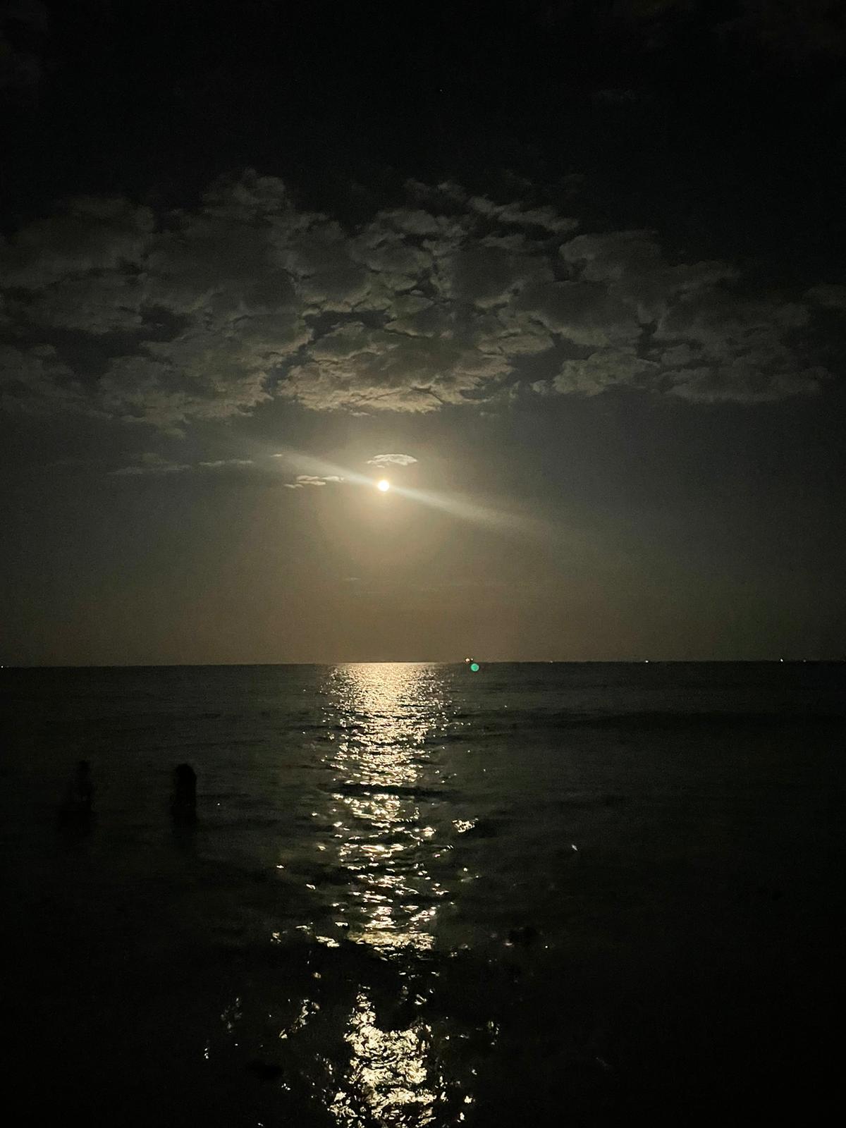 Night photo with a full moon and clouds on the open water