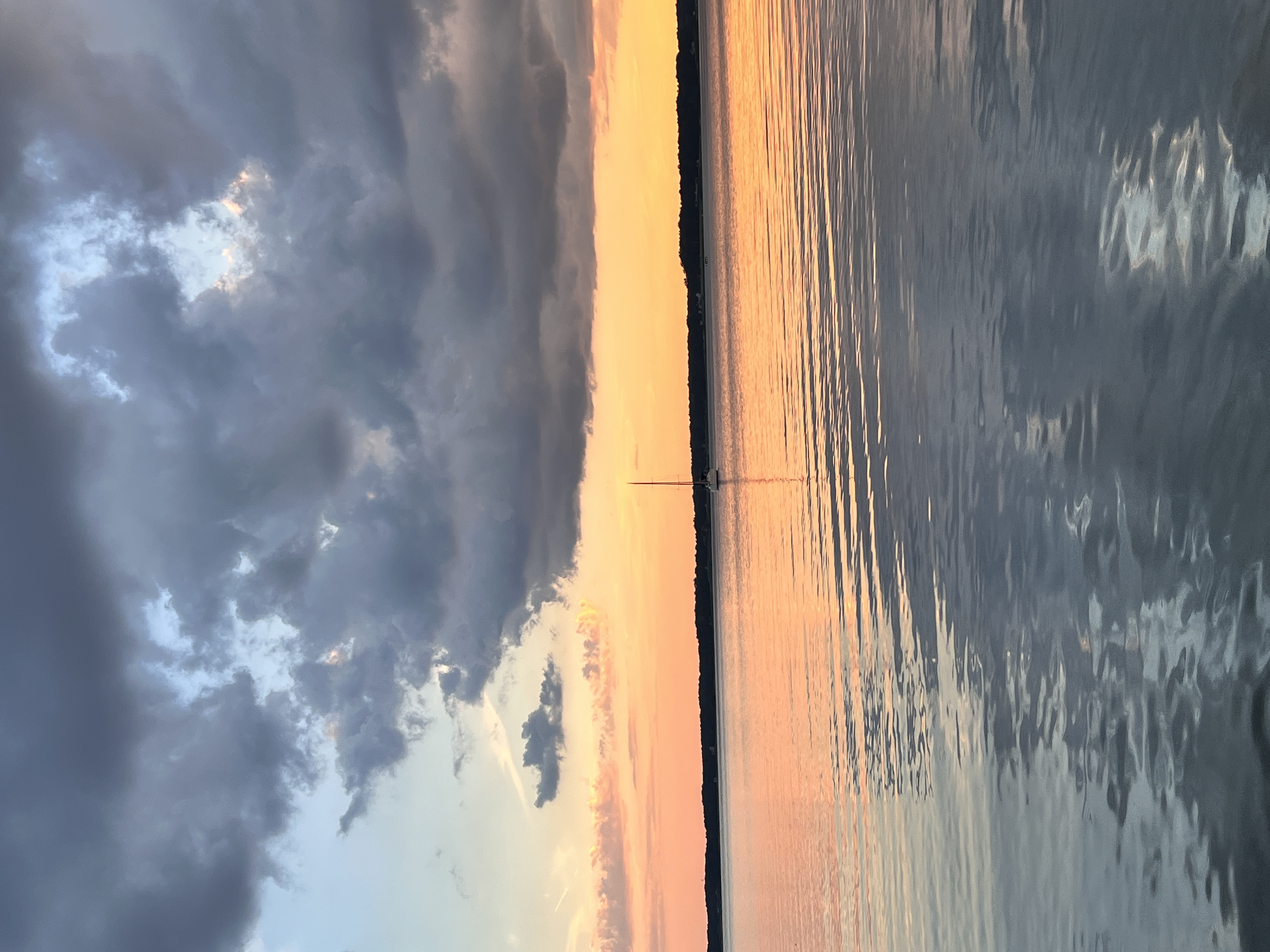 Photo of a calm section of the Intercoastal Waterway on the east coast before sunrise and a sailboat in the distance