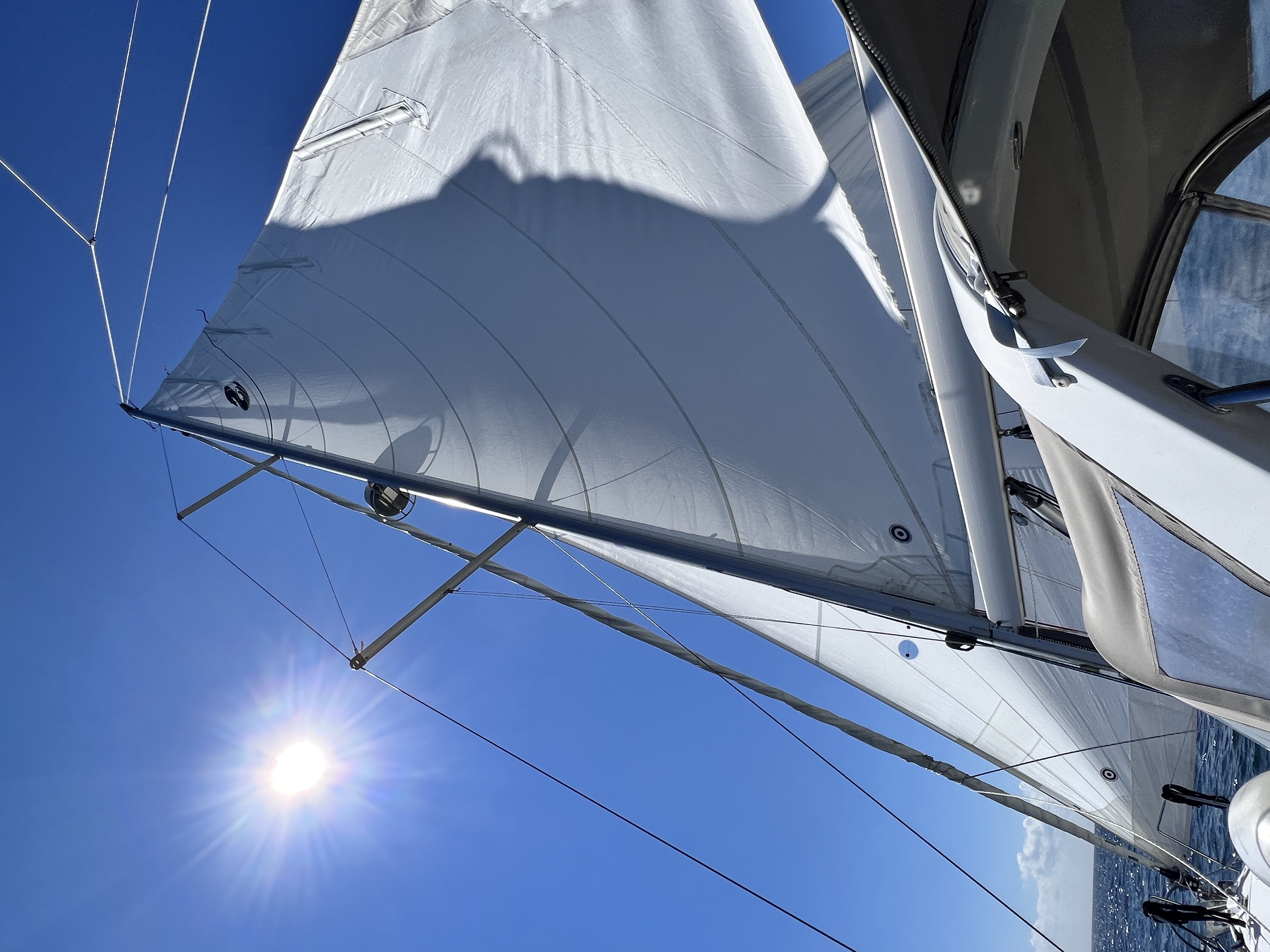 Photo of open sails in a blue sky with bright sunlight
